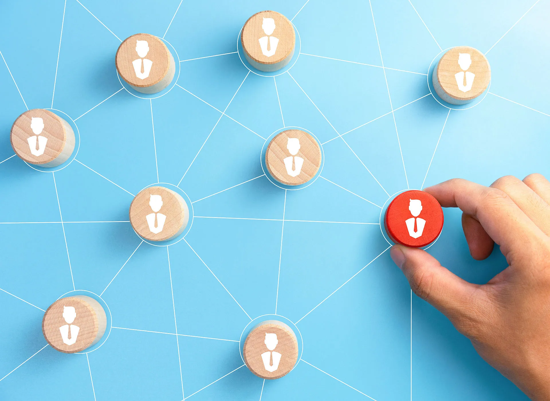 Vor einem hellblauen Hintergrund sind mehrere Holzchips mit Personensymbolen in einem Netzwerk verbunden.
