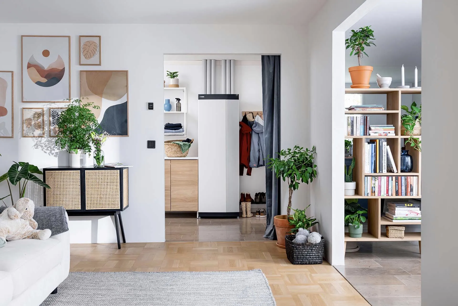 Ein modern eingerichtetes Wohnzimmer mit Blick auf einen Flur, in dem eine schlanke Wärmepumpe installiert ist