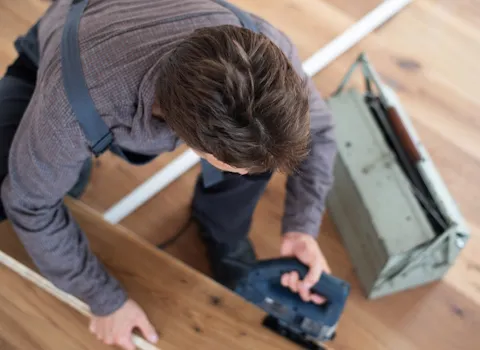 Schreiner SHK schneidet Holzdielen zurecht. 