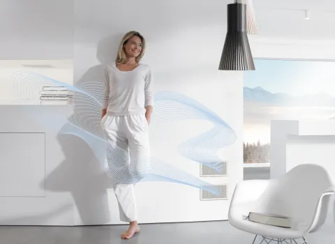 Lüftung und Raumwärmer von Zehnder mit hell gekleideten Frau vor einer weißer Wand