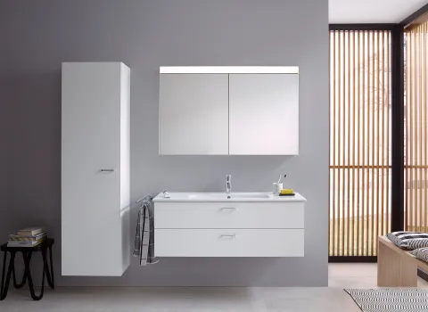 Die Badmöbelserie XBase von Duravit zeigt einen weißen Waschtisch mit Spiegelschrank, Hochschrank und einem stilvollen, hellen Interieur.