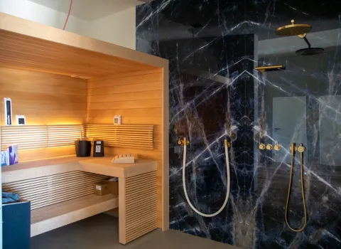 Sauna und Walk-In-Regendusche mit blauer Wand in Marmoroptik in der Badausstellung Ahrensburg der Prehn & von Hoeßlin GmbH & Co. KG.