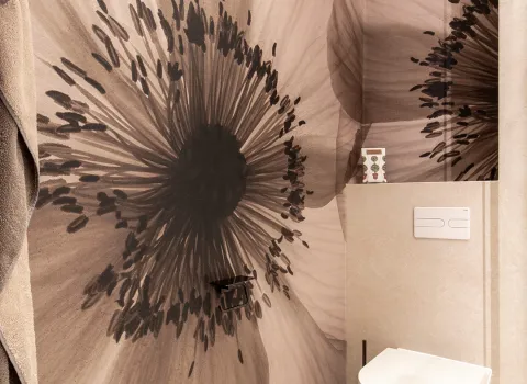 Florales Wanddesign neben dem WC im Referenzbad der Prehn & von Hoeßlin GmbH & Co. KG.