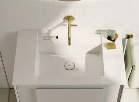 Ein kompakter, moderner Waschtisch in Weiß steht unter einem runden Spiegel und ist mit einer goldfarbenen Armatur stilvoll ergänzt.