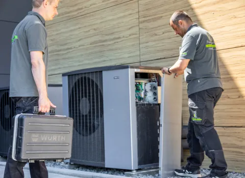 Zwei Mitarbeiter von Prehn & von Hoeßlin arbeiten an einer geöffneten Wärmepumpenanlage im Außenbereich.