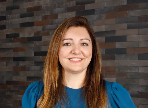 Elena Schwabauer, Mitarbeiterin von Prehn & von Hoeßlin GmbH & Co. KG, Porträtaufnahme vor einer Steinwand.