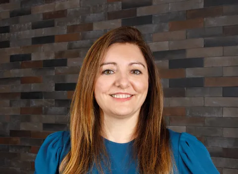 Elena Schwabauer, Mitarbeiterin von Prehn & von Hoeßlin GmbH & Co. KG, Porträtaufnahme vor einer Steinwand.