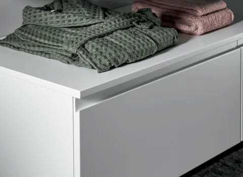 Minimalistisches Stocco Badmöbel in Weiß mit grifflosen Schubladen und dekorativ gefalteten Textilien.