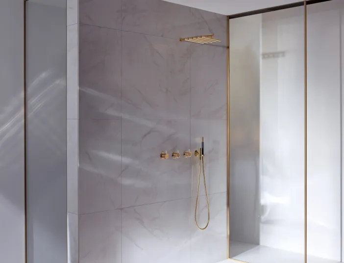 Duschfläche BetteFloor in Naturstein-Dusche mit goldenen Armaturen