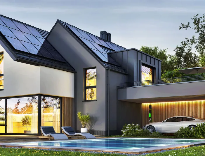 Das Bild zeigt ein energieeffizientes Einfamilienhaus mit Solaranlage, Elektroauto-Ladestation und einem Pool im gepflegten Garten.