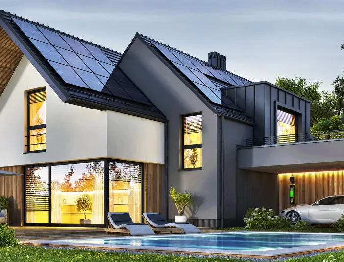 Einfamilienhaus mit Photovoltaikanlage auf dem Dach, Elektroauto mit Ladestation und Pool im Garten.