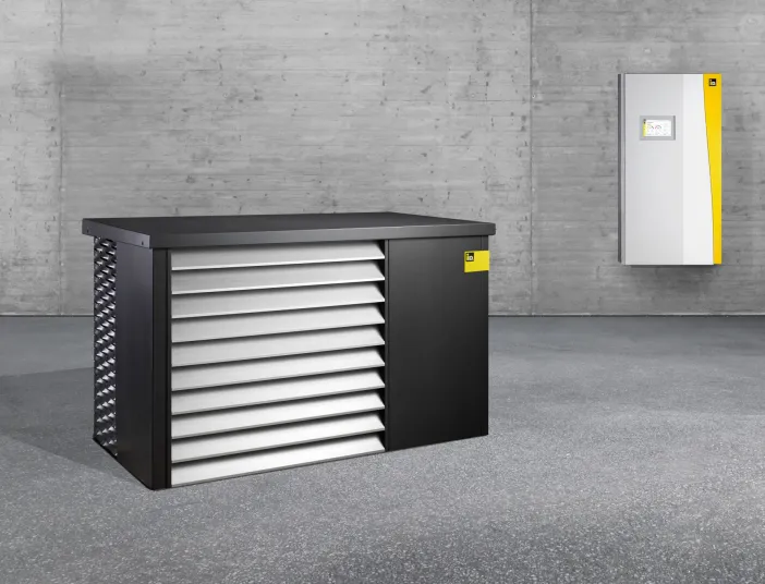 Innen- und Außeneinheit der Wärmepumpe iDM AERO ALM 2-8 und 4-12 in einem leeren, grauen Raum.